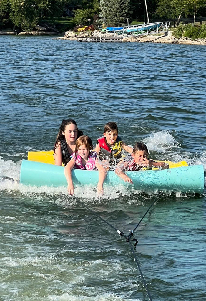 Picture of 4 kids tubing with the Lily Surfer Kit from LilySetter.com. Kids are having a blast, smiling and enjoying this product that is new to the market and taking over the water sports and family lake fun markets